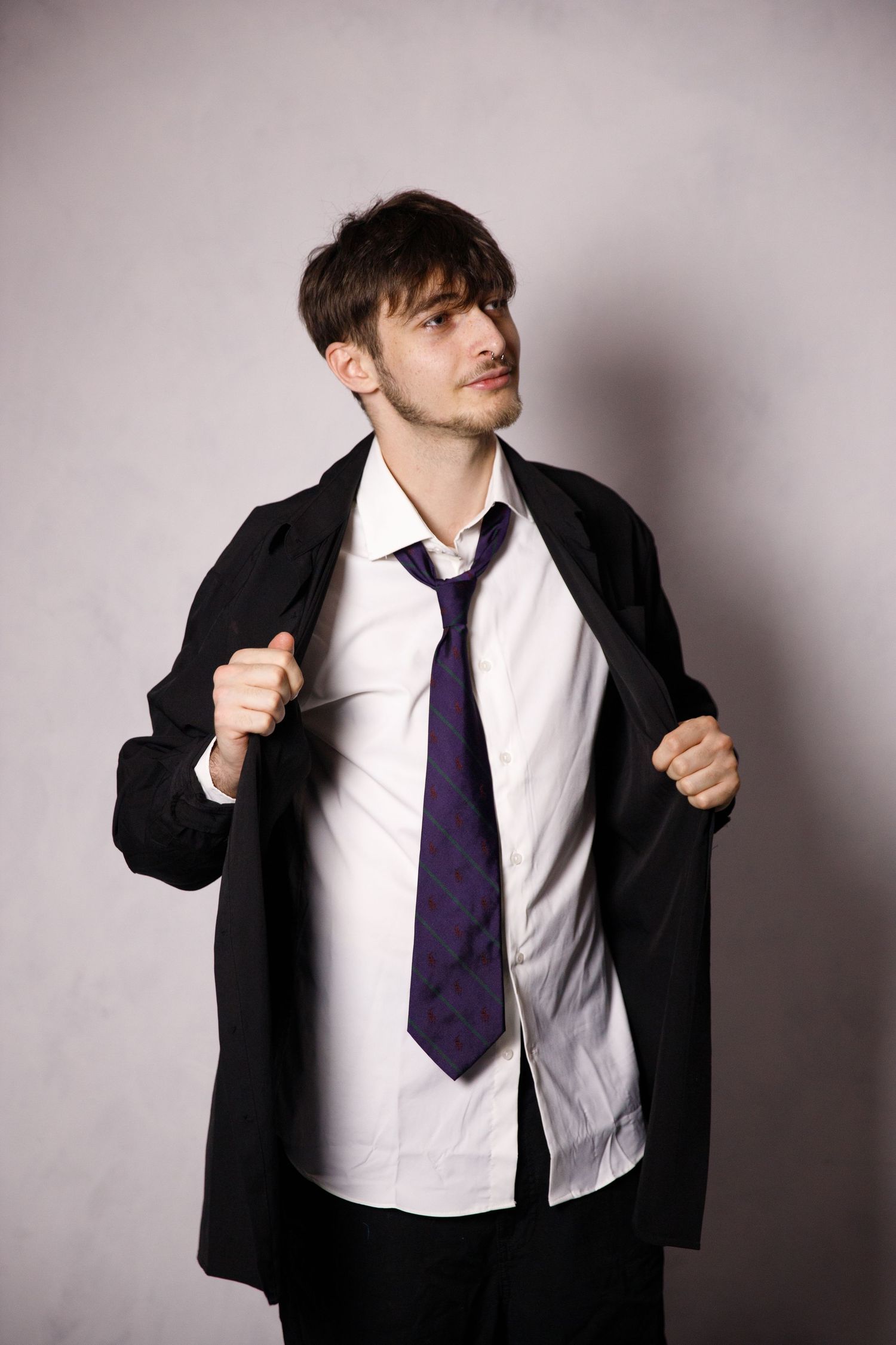 Dynamic poses of someone wearing a black suit jacket, white shirt and purple tie.
