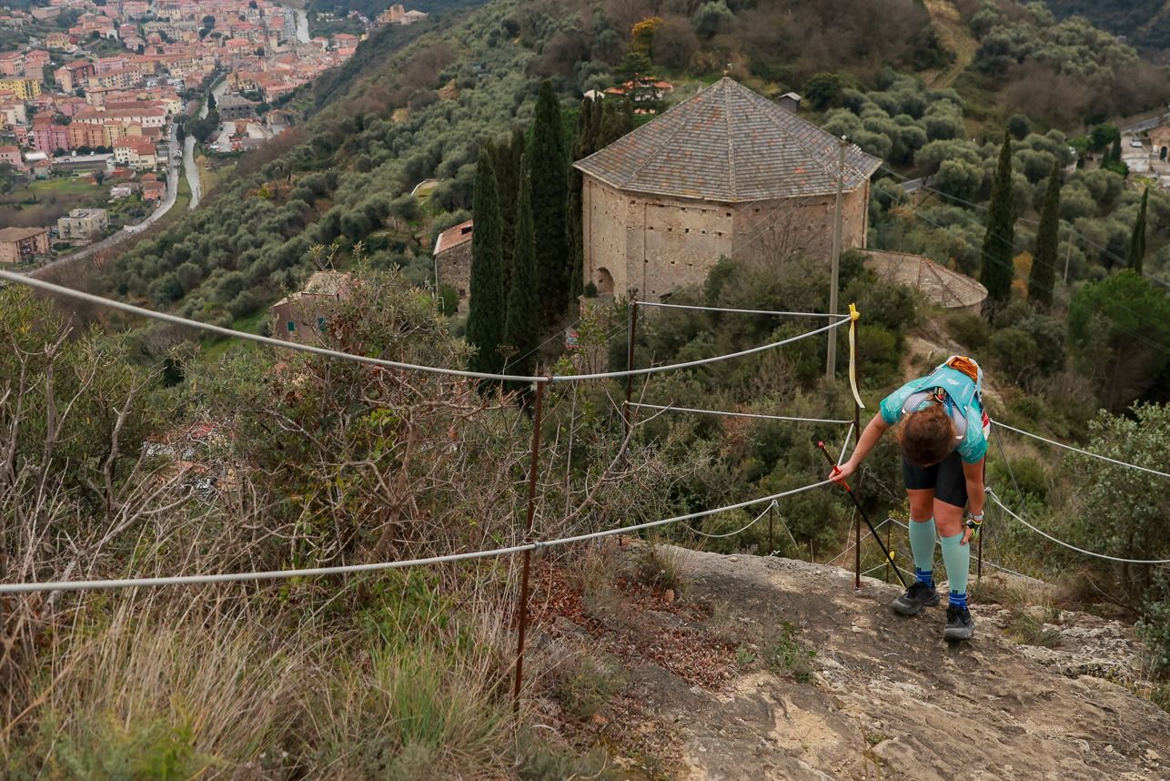 Adventurous hikers traverse a steep mountain trail with ropes and safety equipment on a challenging via ferrata route.