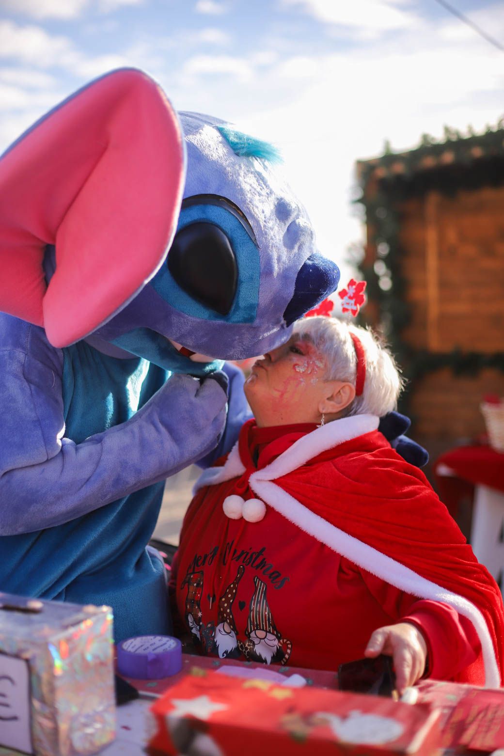 Costumed characters interacting playfully on a red sleigh during a holiday event.