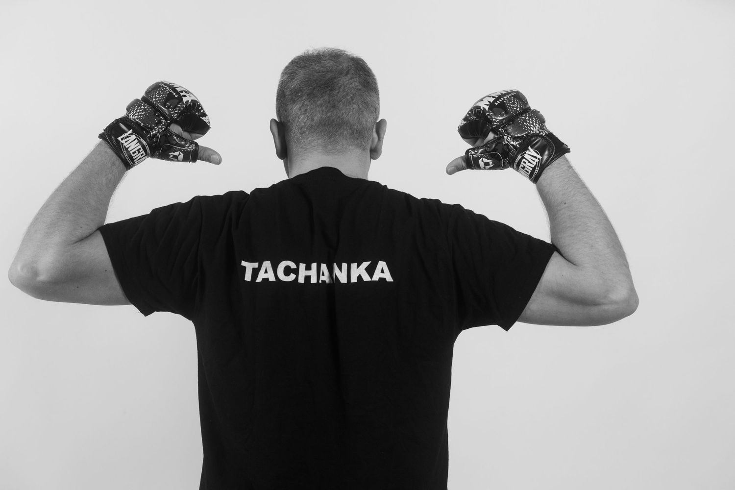 A person wearing a black Tachanka t-shirt shown from behind in multiple poses with arms raised.