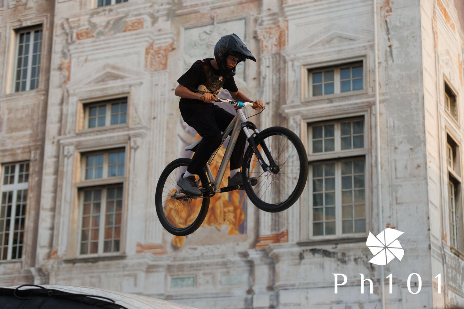 Sequence of BMX bike stunts showing rider jumping against ornate building background.