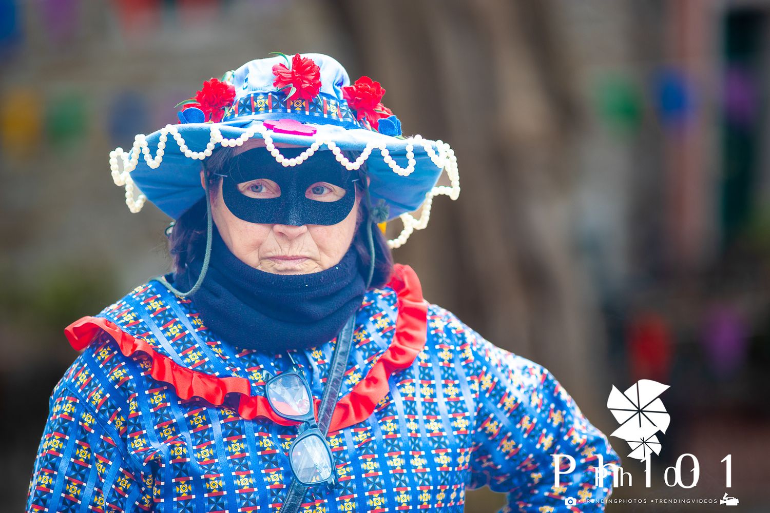 A performer wearing a blue and red patterned costume with a matching hat performs on stage.