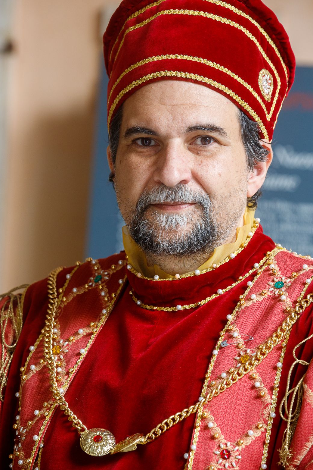 Person wearing ornate red and gold ceremonial costume with decorative trim.