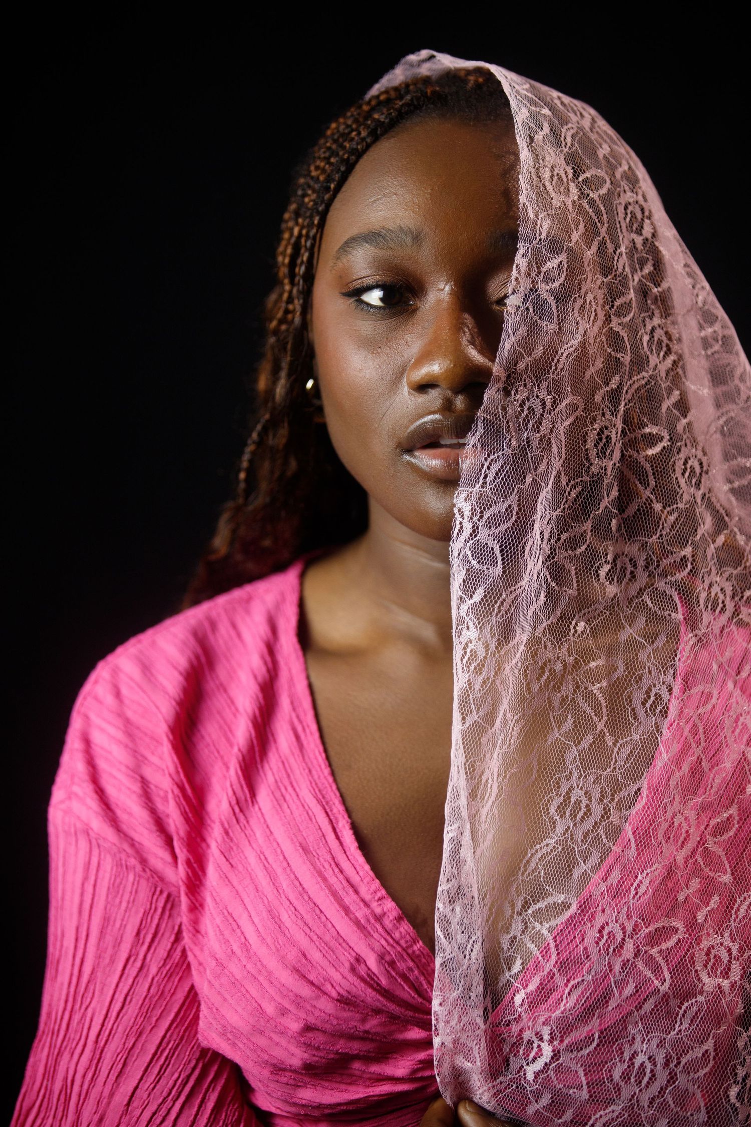 Portrait series with pink lace veil creating ethereal effect against dark background.
