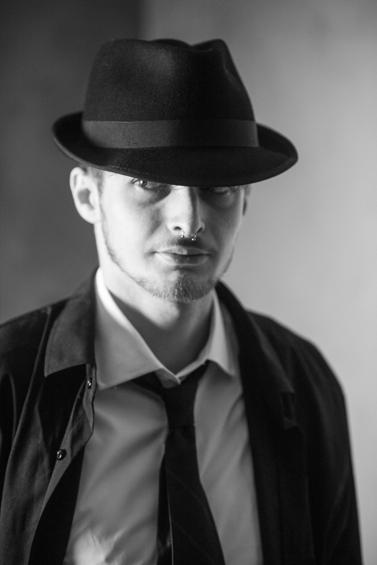 Film noir style portraits featuring a black fedora hat and formal attire in dramatic lighting.