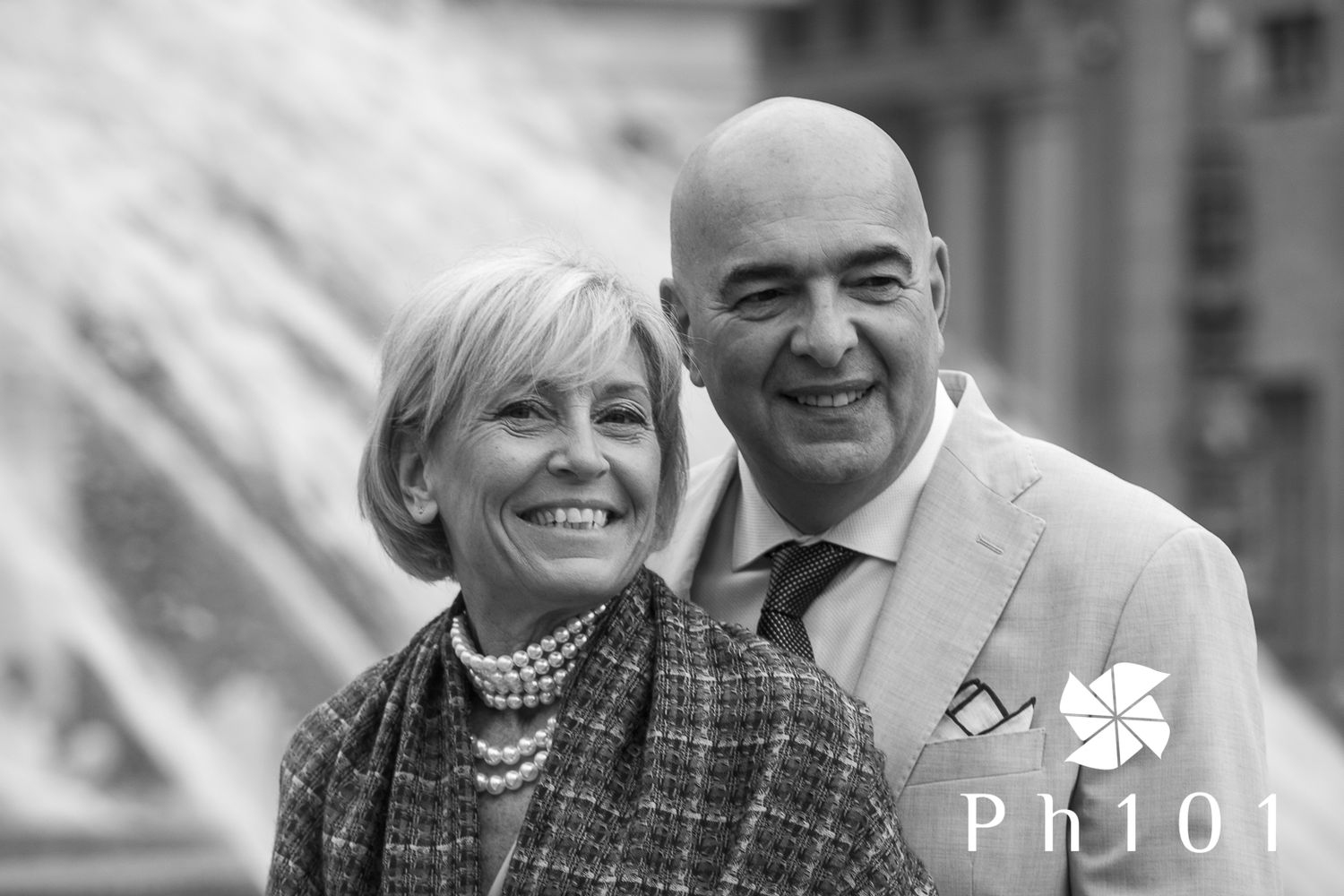 Smiling couple in matching grey and beige formal wear posing for a portrait.