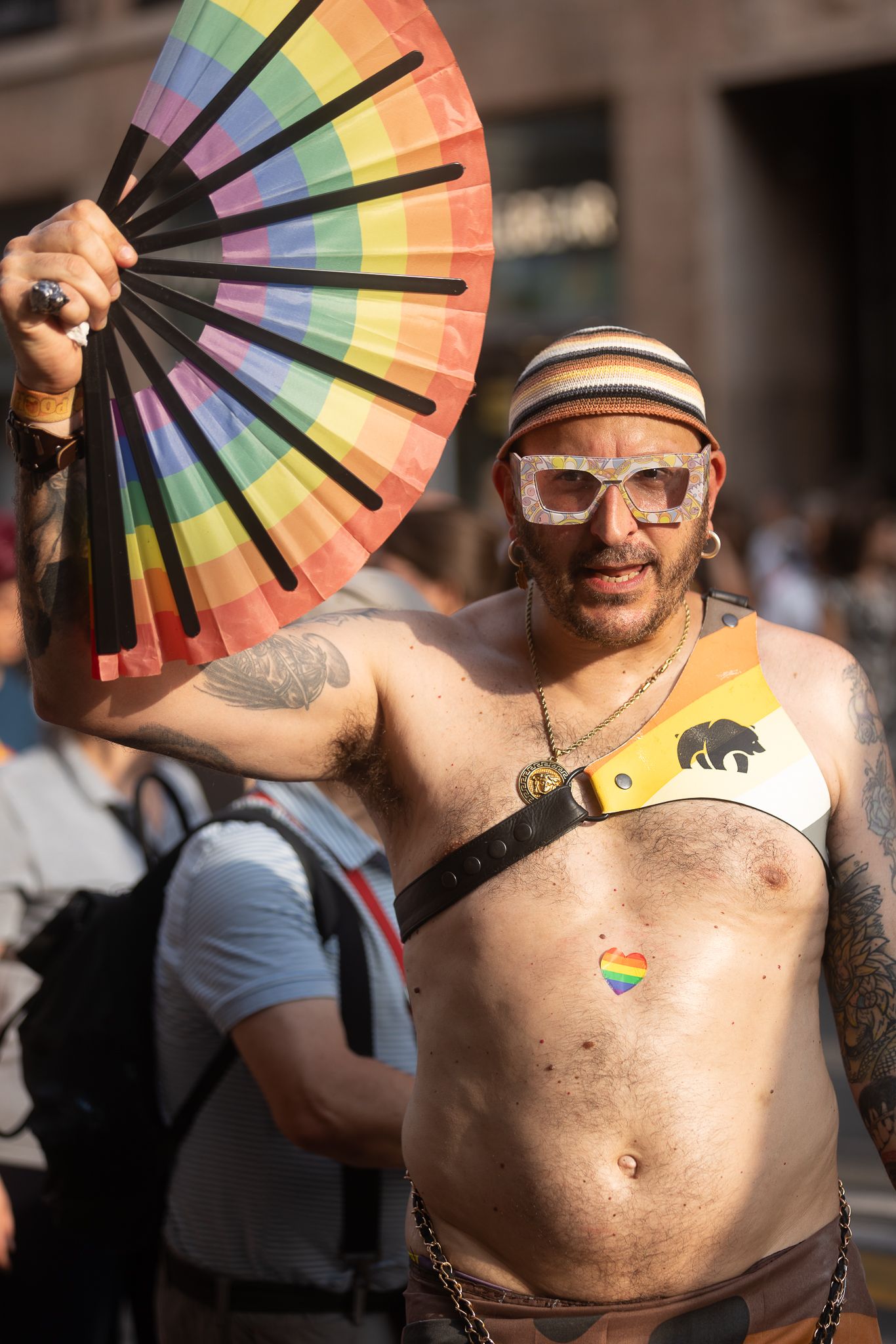 Pride celebration with rainbow hand fans in bright sunlight.