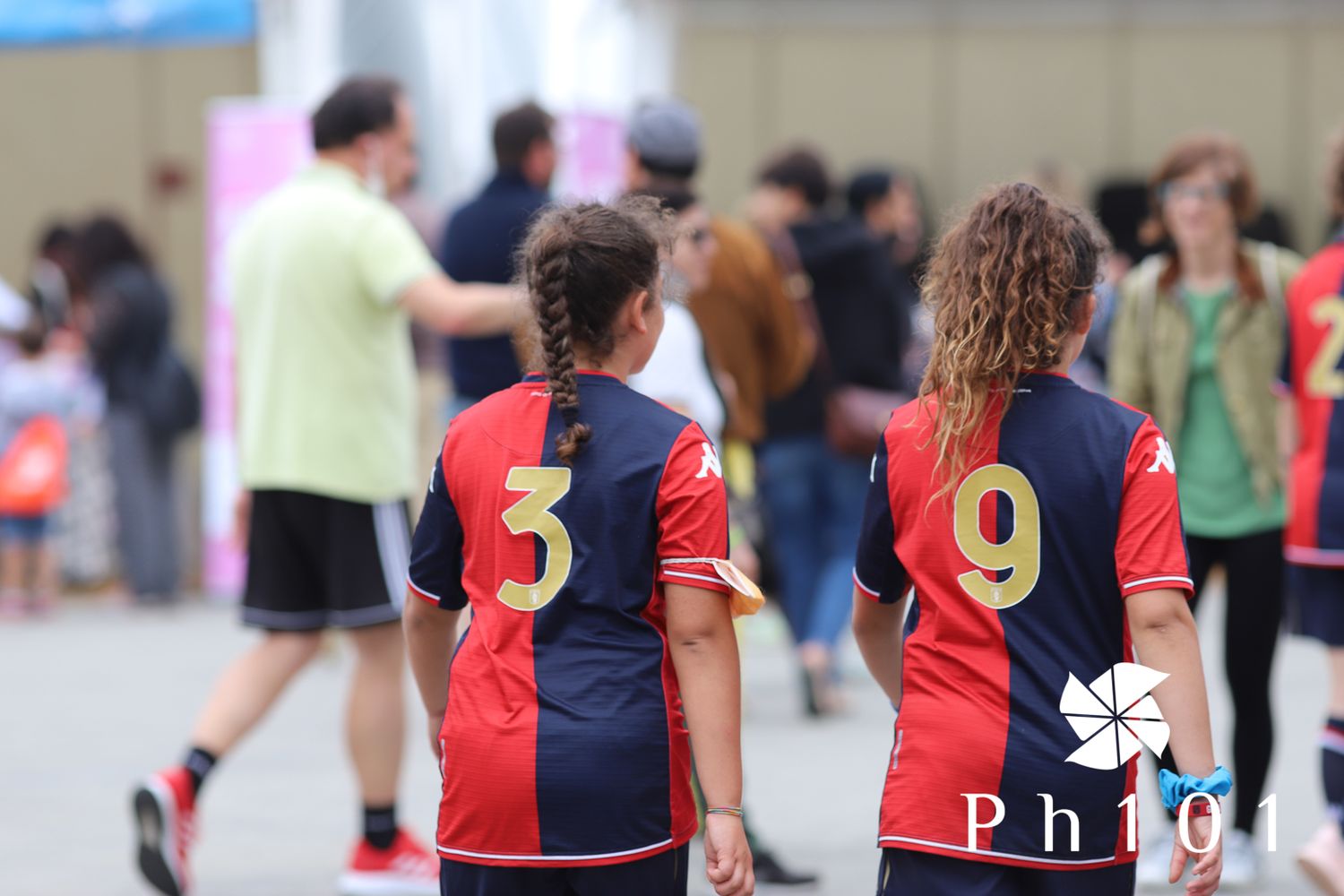 Soccer players wearing red and blue striped jerseys numbered 5 and 9 from behind.