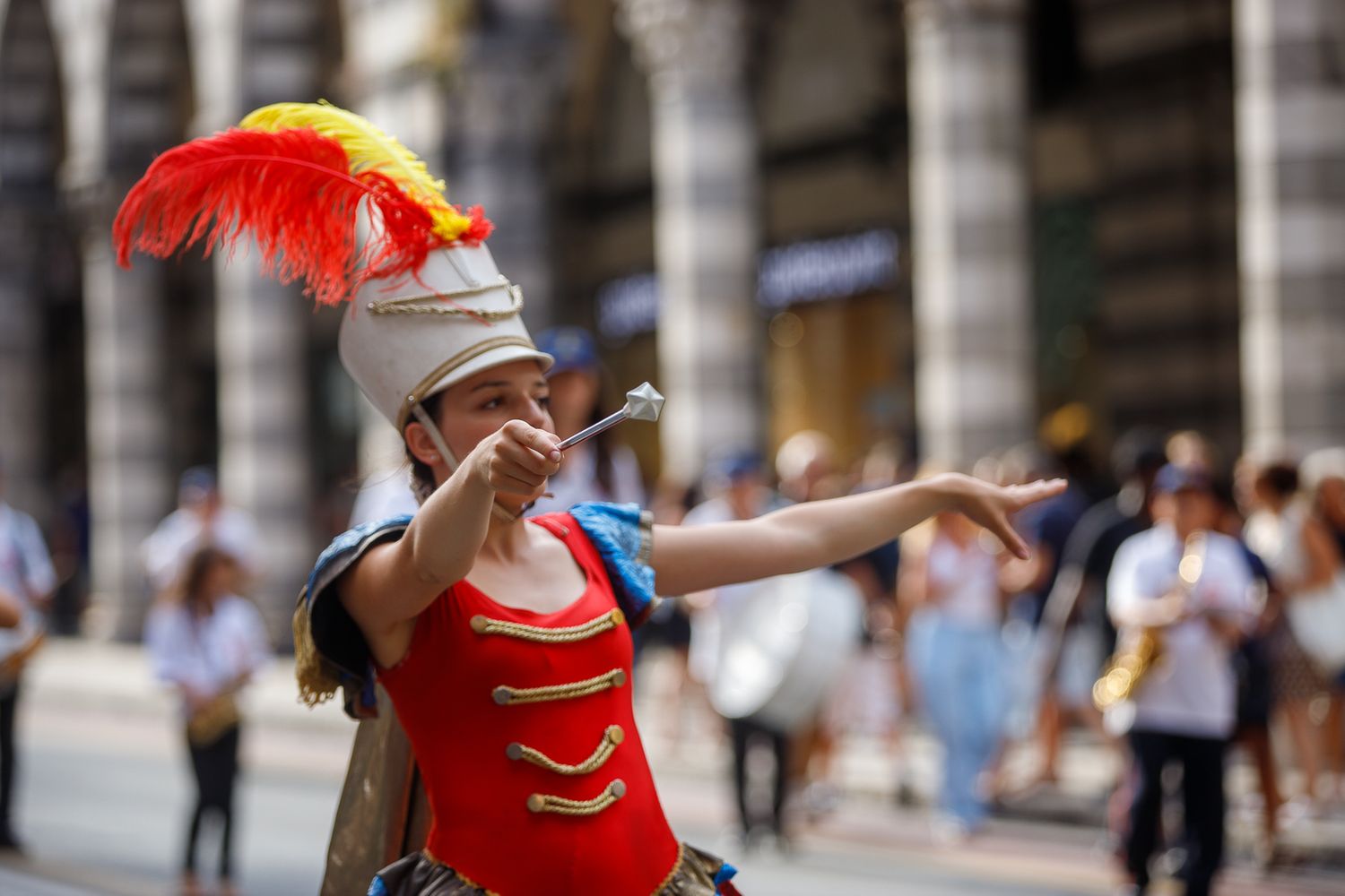 Dancers in vibrant red costumes perform synchronized movements on a cobblestone street.