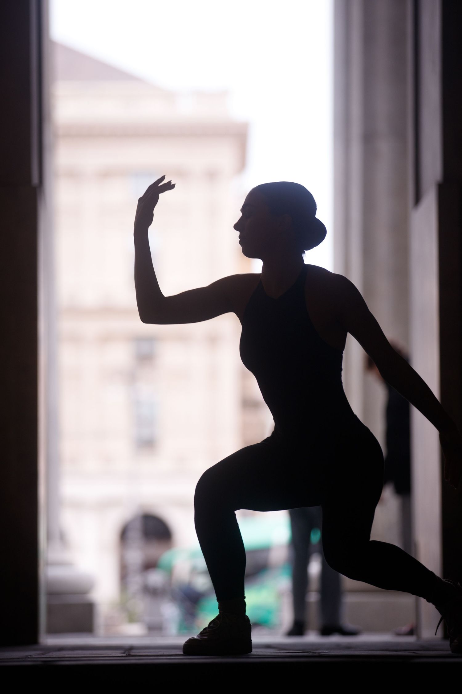 Silhouette sequence of figure dancing and posing in window frame.