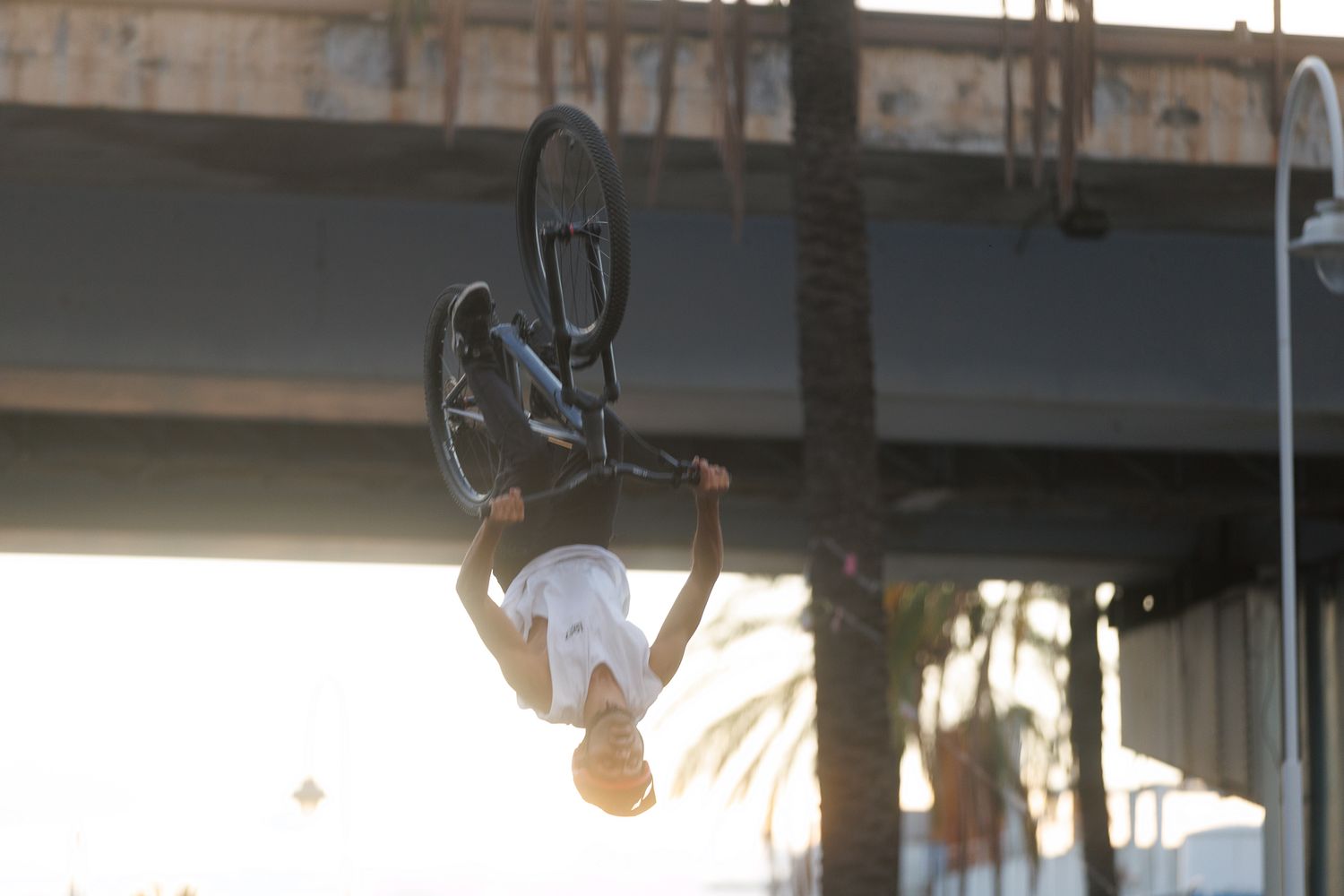 BMX riders execute aerial tricks with a historic building backdrop at sunset.