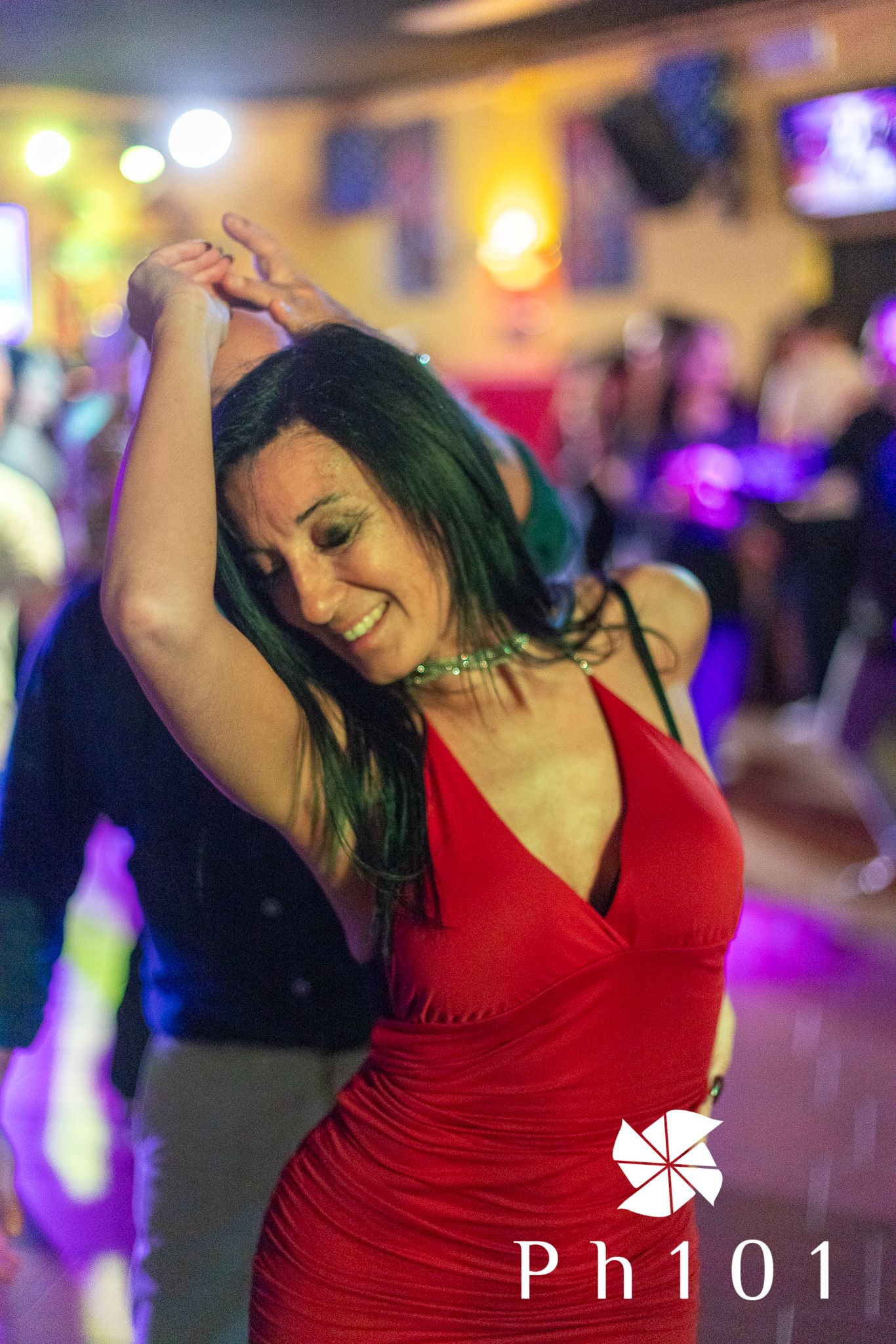 Woman in red dress dancing under colorful party lights.