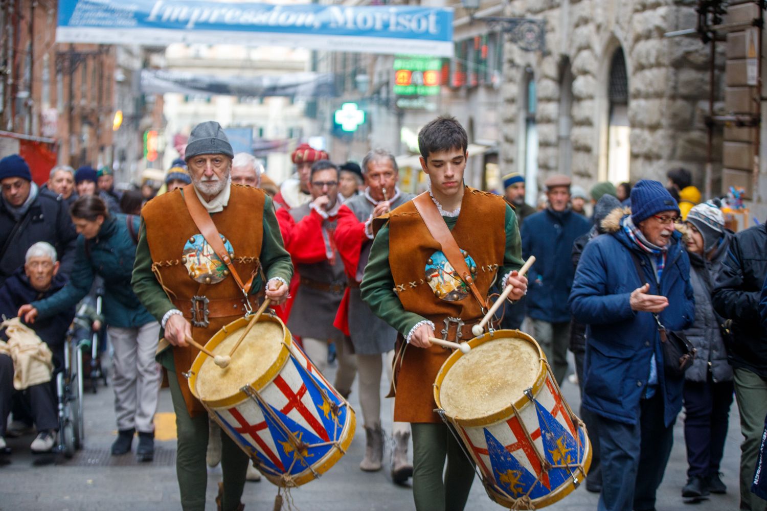 Historical reenactors march with drums and instruments during an outdoor festival.