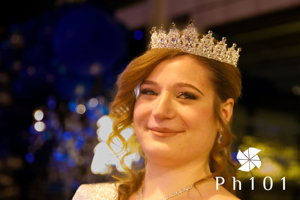 Person wearing a crown and formal attire at an evening celebration.