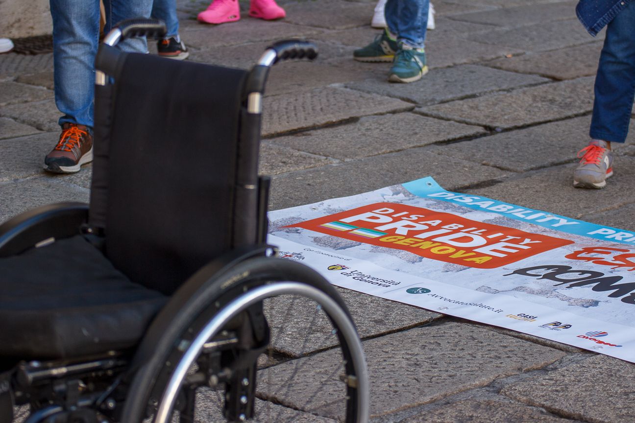 Empty wheelchair and protest signs visible on cobblestone street.