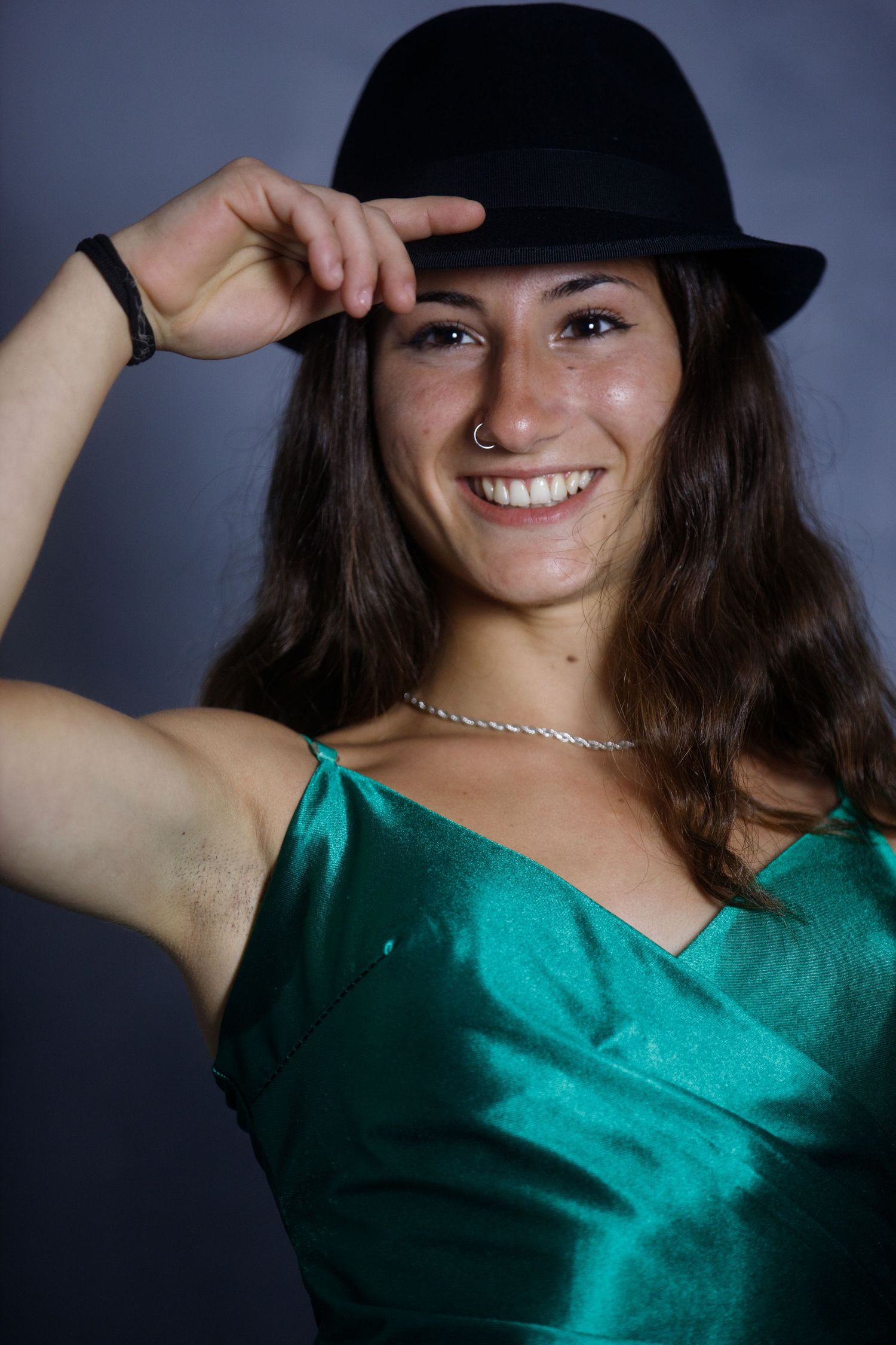 Playful fashion portraits in a green satin top and black hat with various poses and expressions.