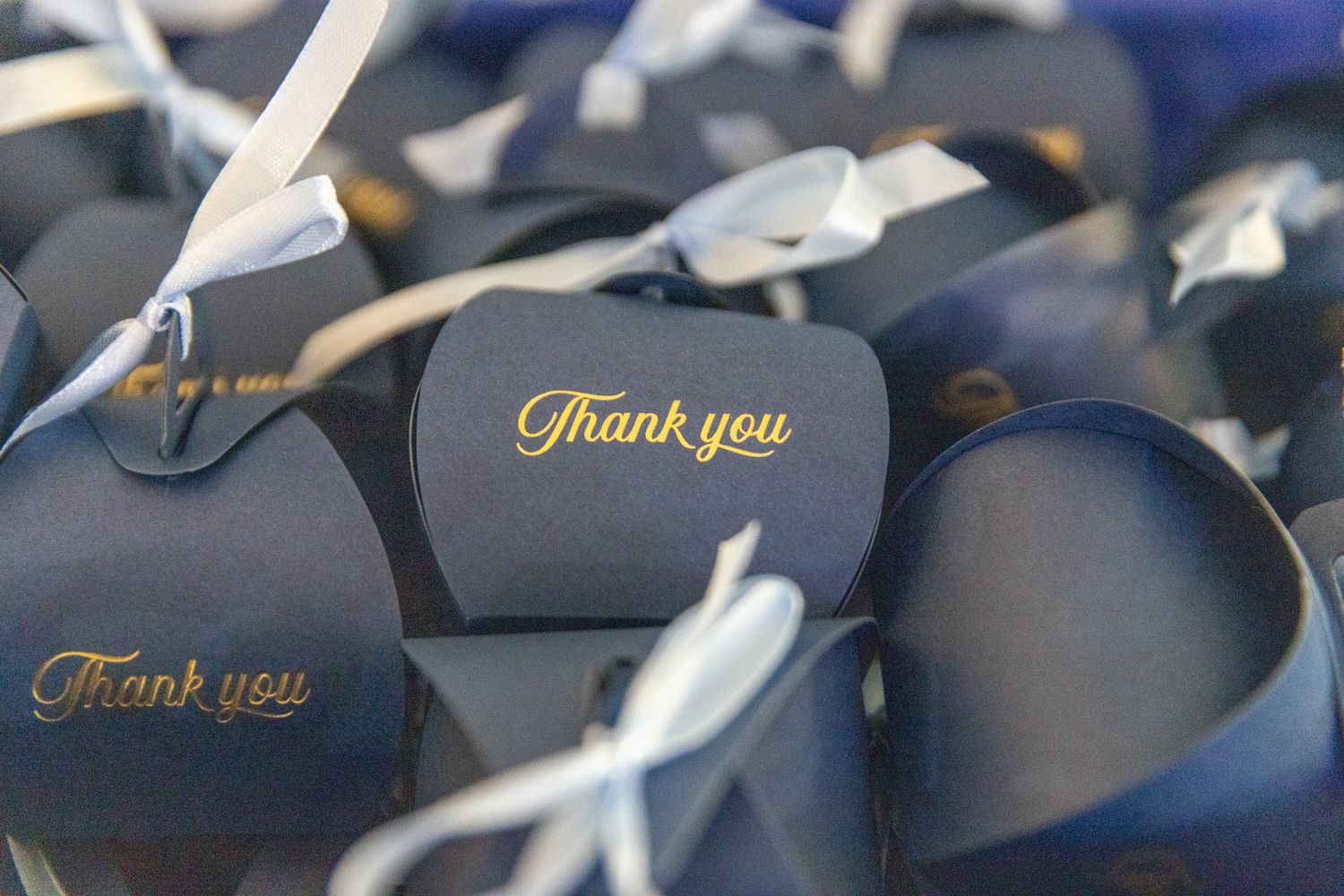 A row of navy blue graduation caps with gold tassels laid out in a line for a graduation ceremony.
