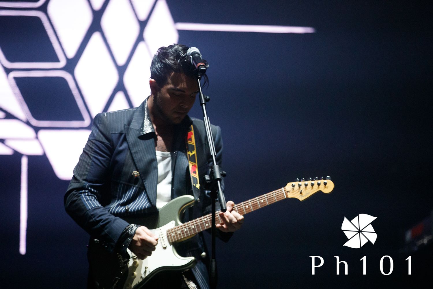 Musicians performing on darkly lit stage with geometric lighting design.