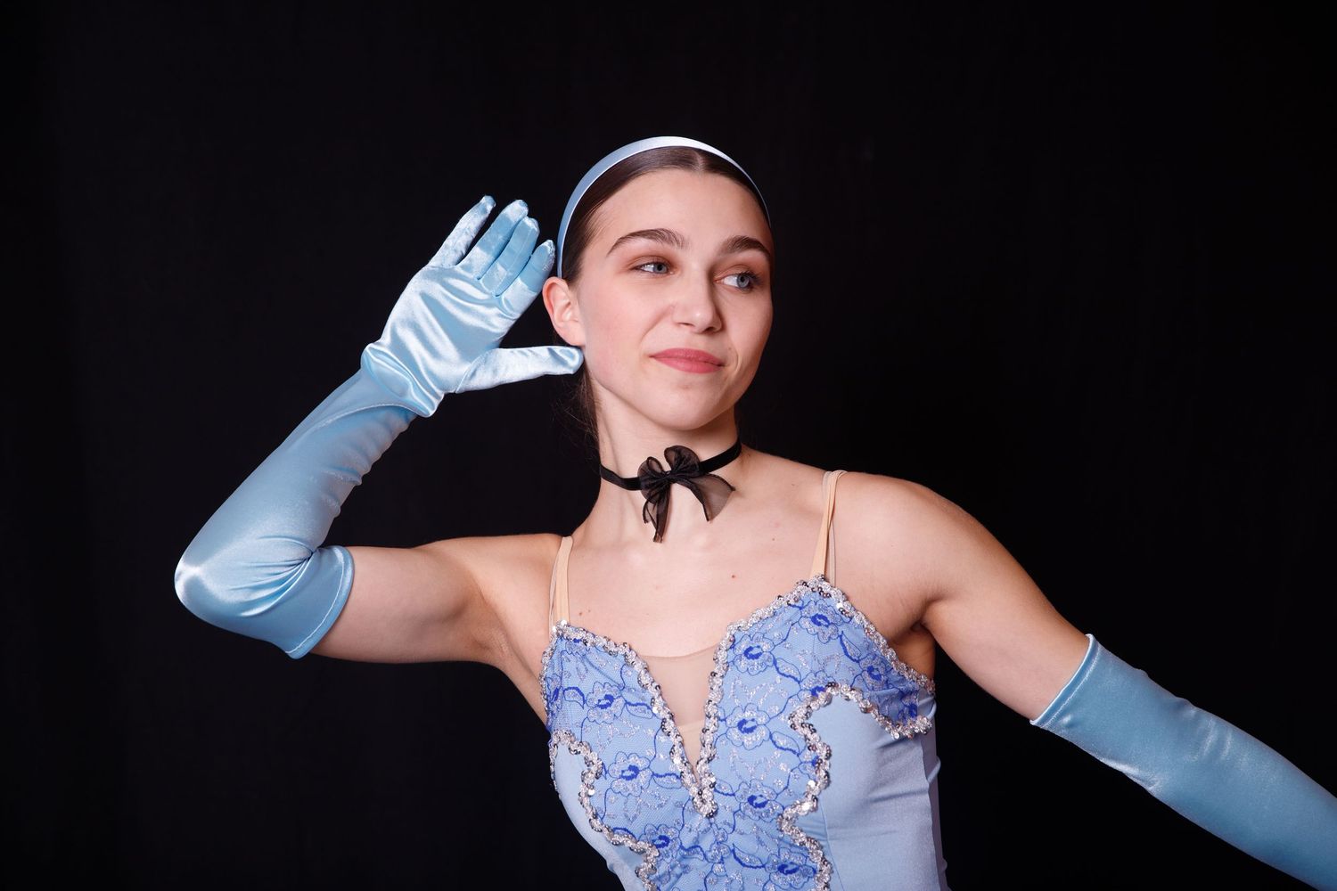 Dancer in light blue costume with long gloves performing expressive gestures.
