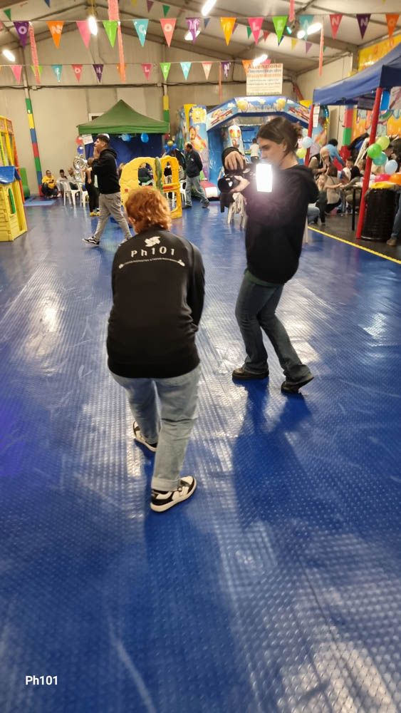 People with cameras filming in a decorated indoor space with blue flooring.