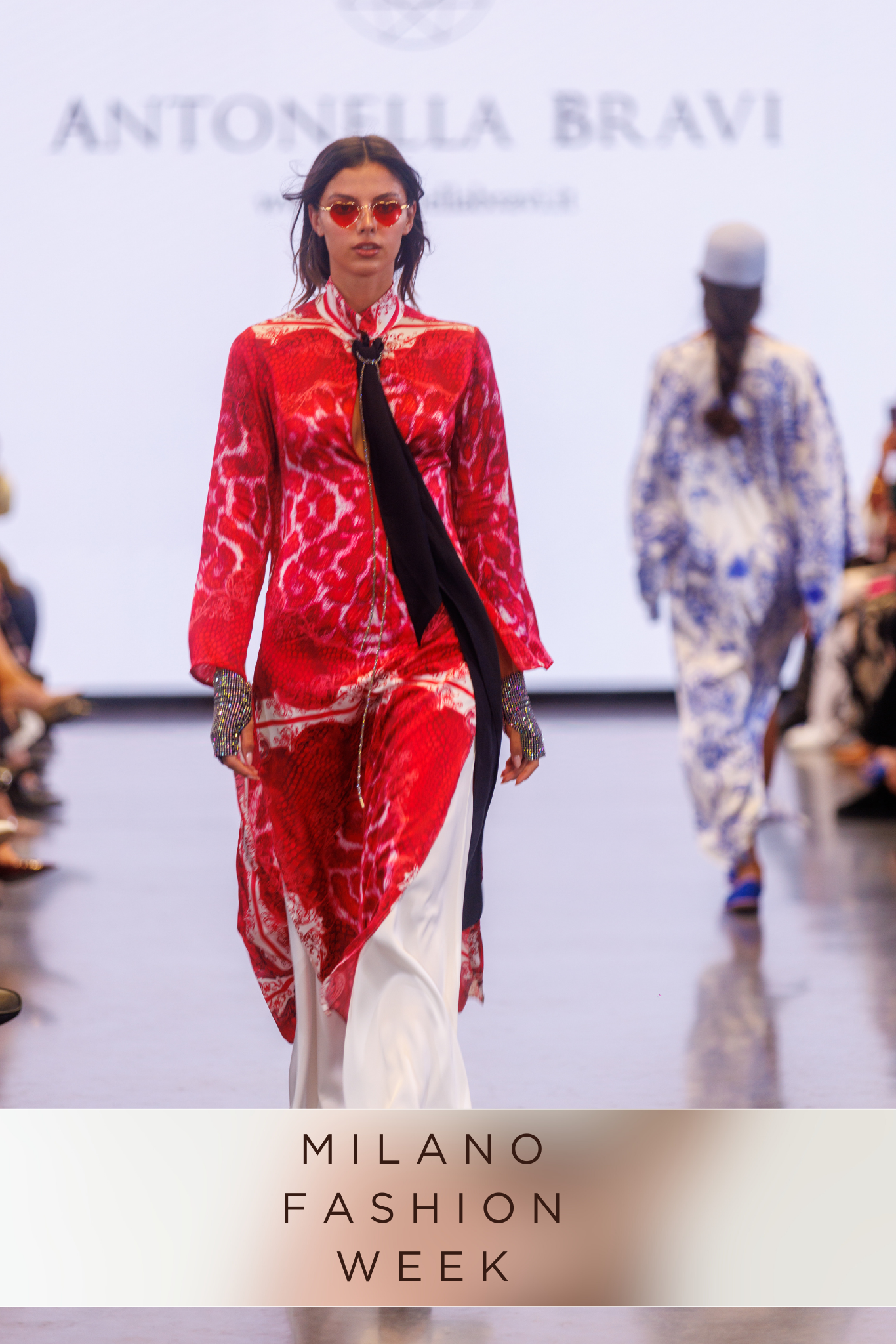 Models walking the runway in red and white designer outfits at Milano Fashion Week.