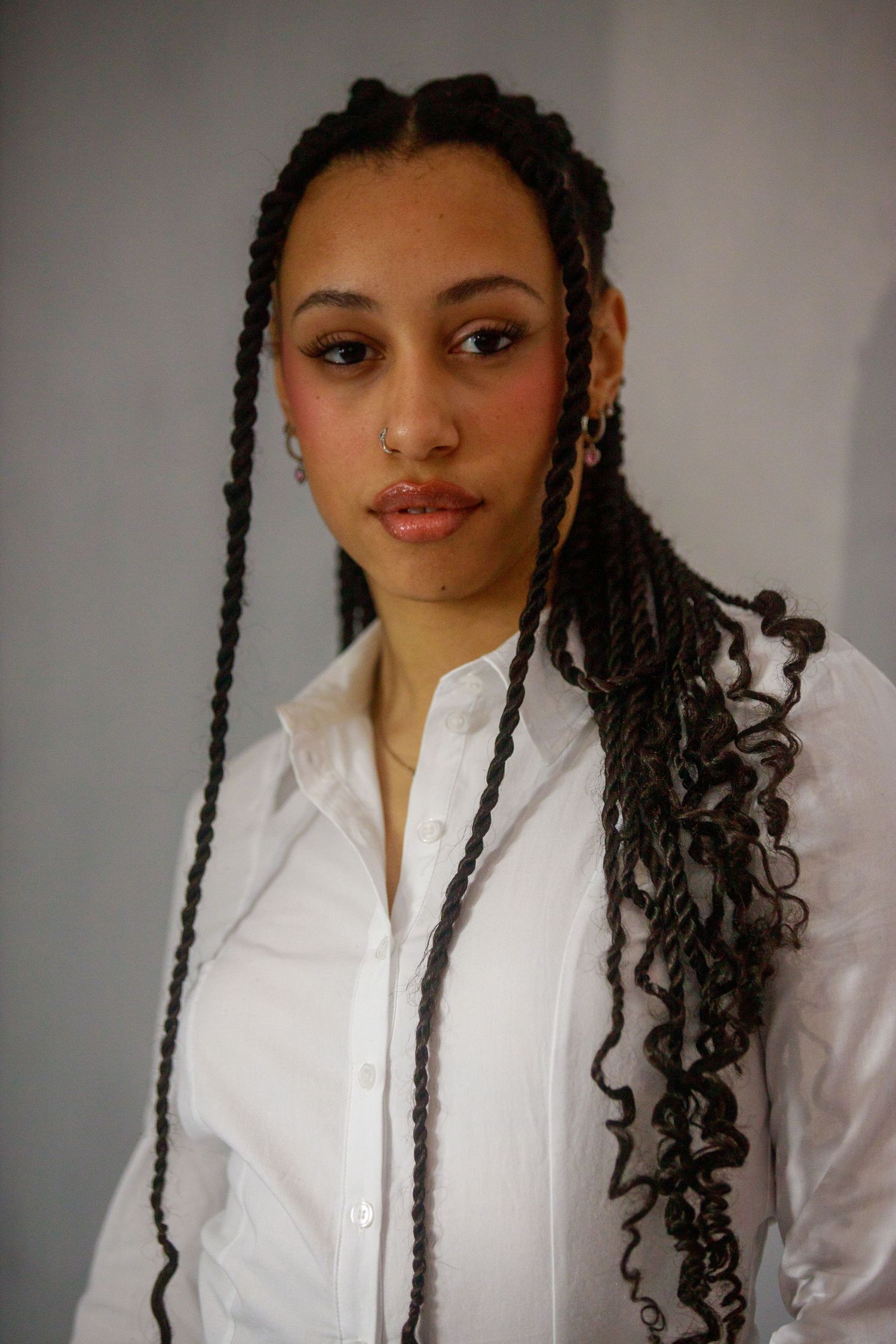 Portrait series showing braided hairstyle and white button-down shirt against light background.