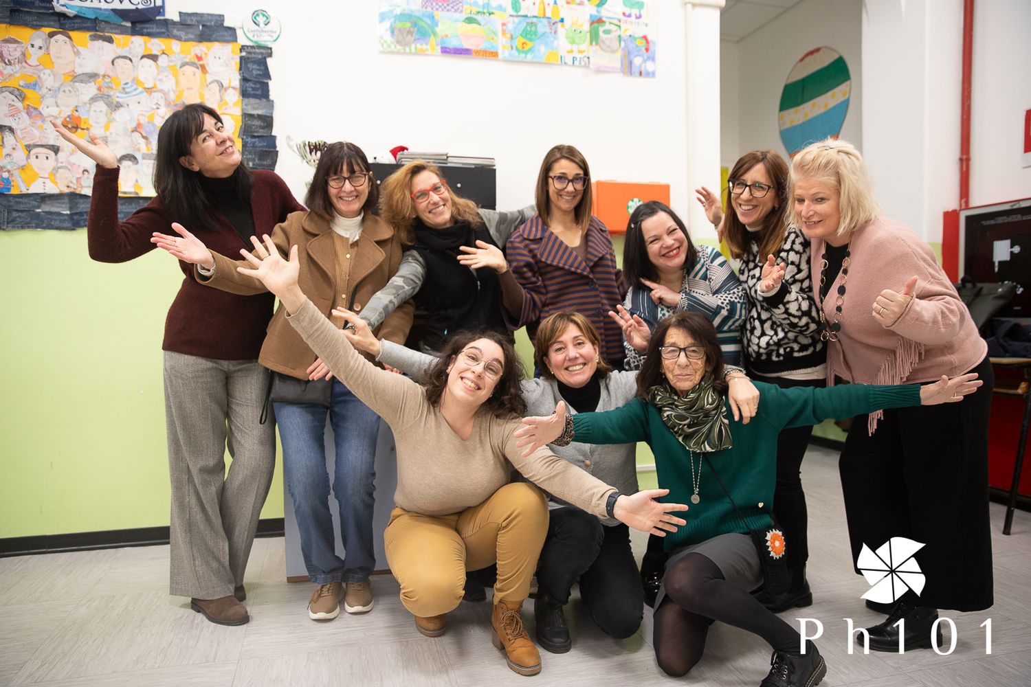 Students posing together playfully in a classroom with colorful wall decorations.