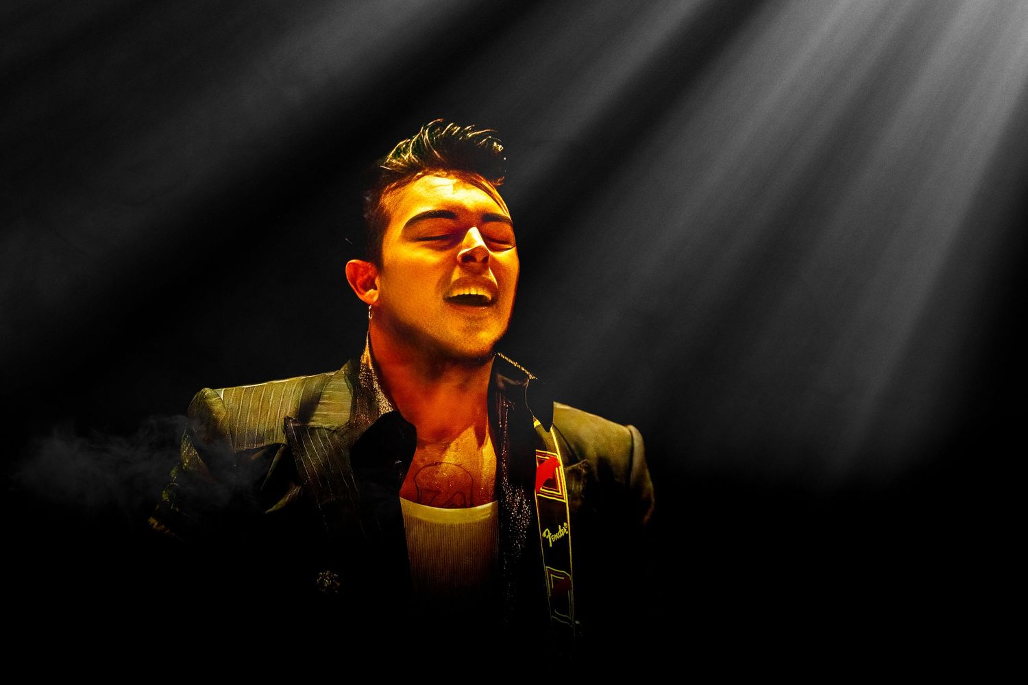 Dramatic spotlit performance with beams of light creating shadows on stage.