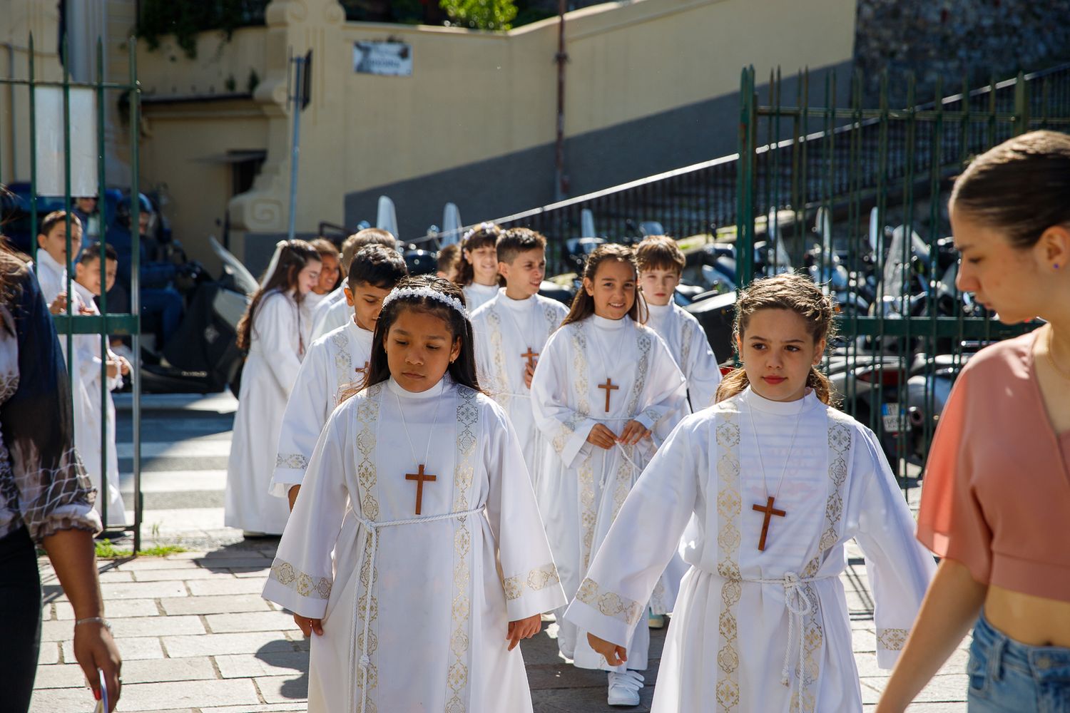 Children in white robes walk in procession during a religious ceremony.