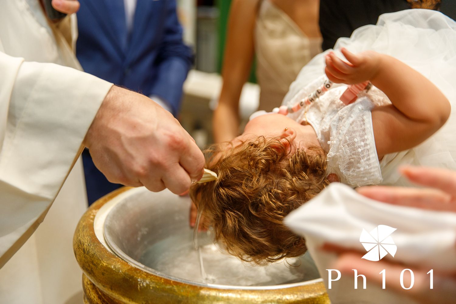 Close-up of a baptism ceremony showing hands pouring water over an infant's head.