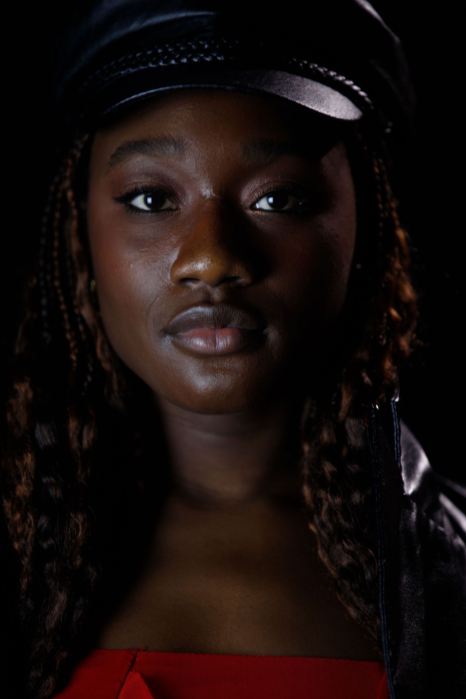 Dramatic portrait series with cap and natural lighting creating moody atmosphere.