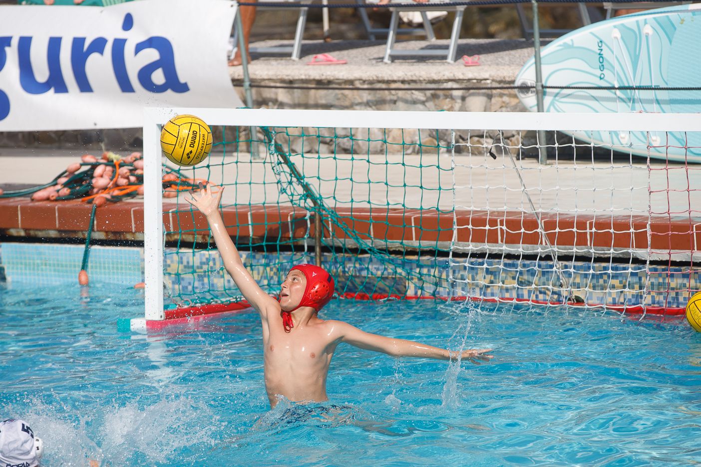 Water polo players competing near the goal net during a match.