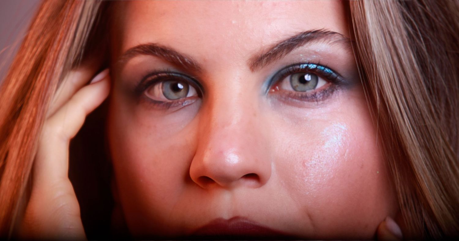 Close-up beauty portrait highlighting striking blue eyes and natural makeup.
