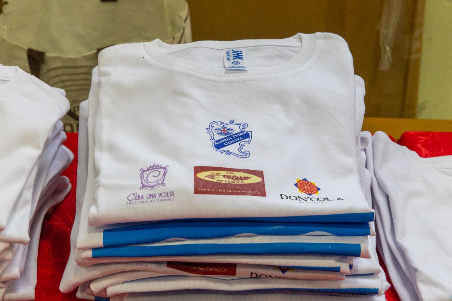 Neatly folded white t-shirts with various logos displayed in a row.