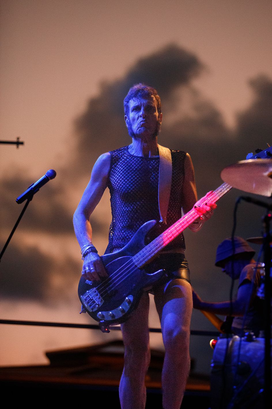 Musician playing bass guitar under blue stage lighting during a performance.
