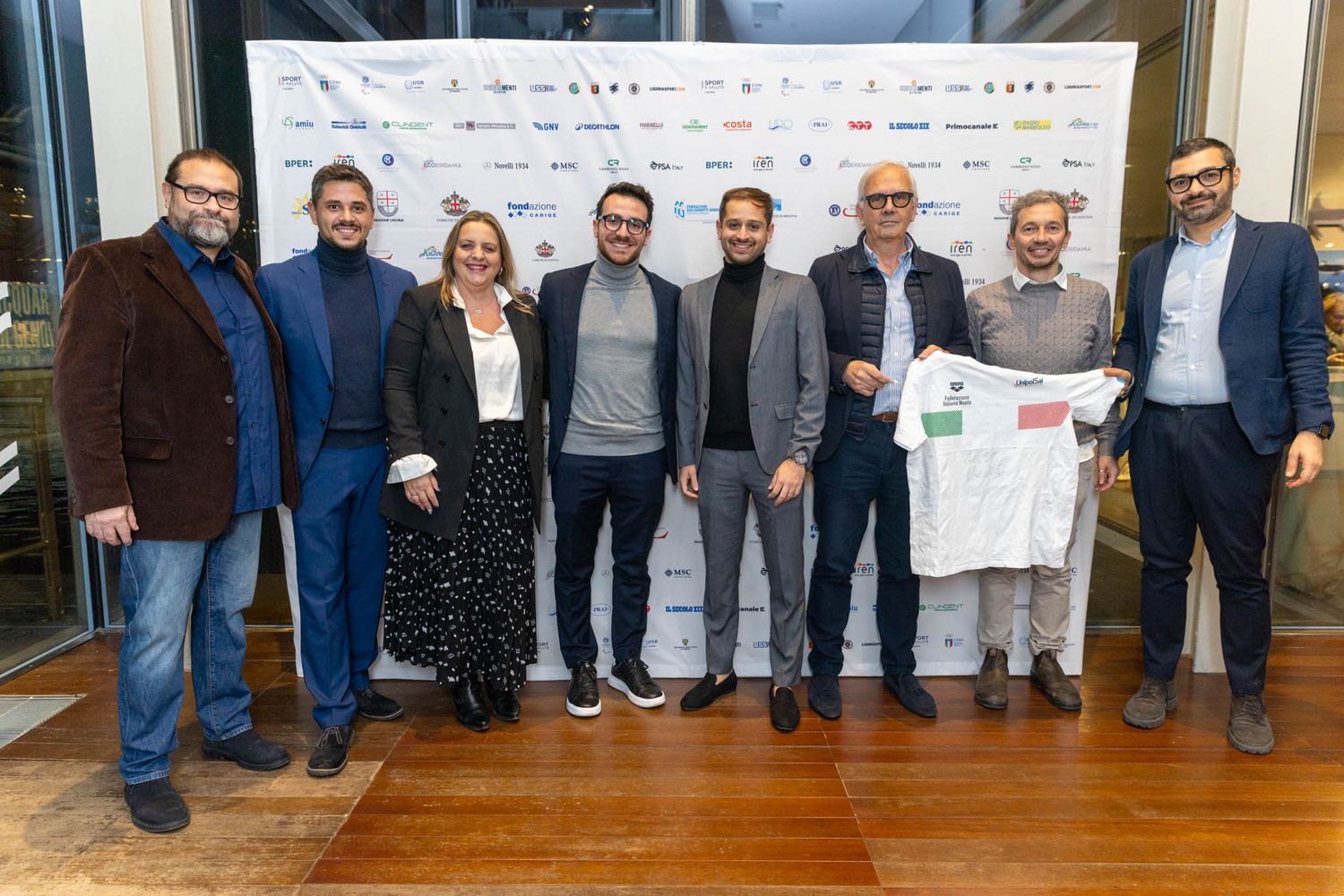 Row of people standing together at formal presentation with banner backdrop.