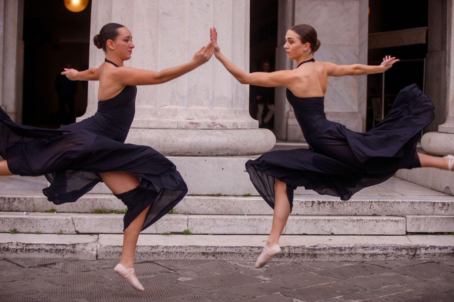 Modern dance sequence showing two performers in flowing black outfits on stone steps.