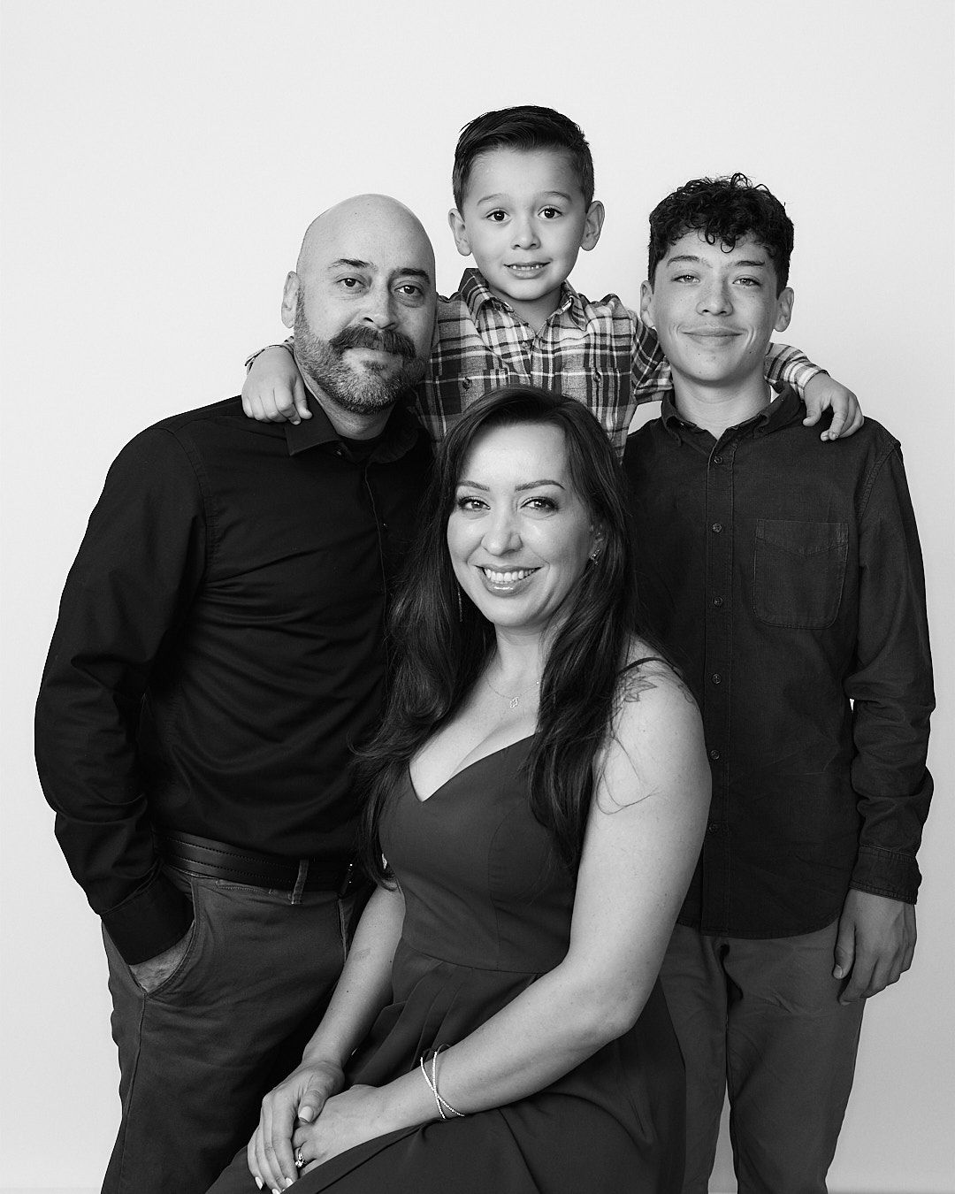 Family portrait series in black and white showing parents and child posing together.