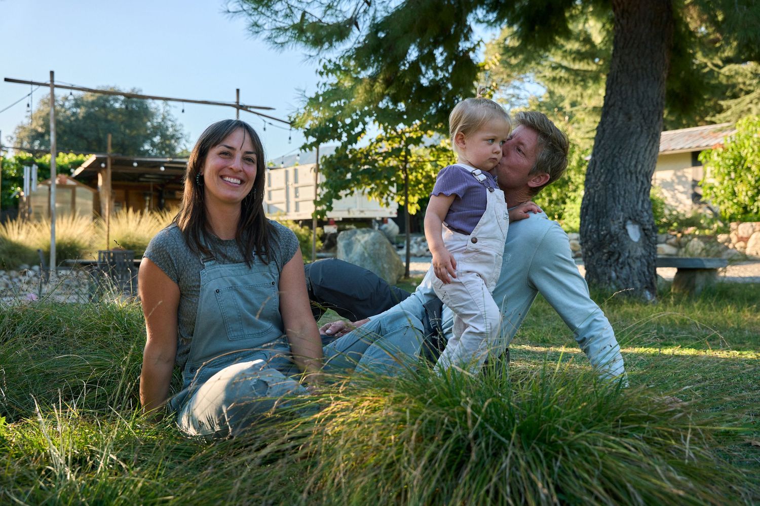 Family lying together on grass during outdoor photo session in natural sunlight.