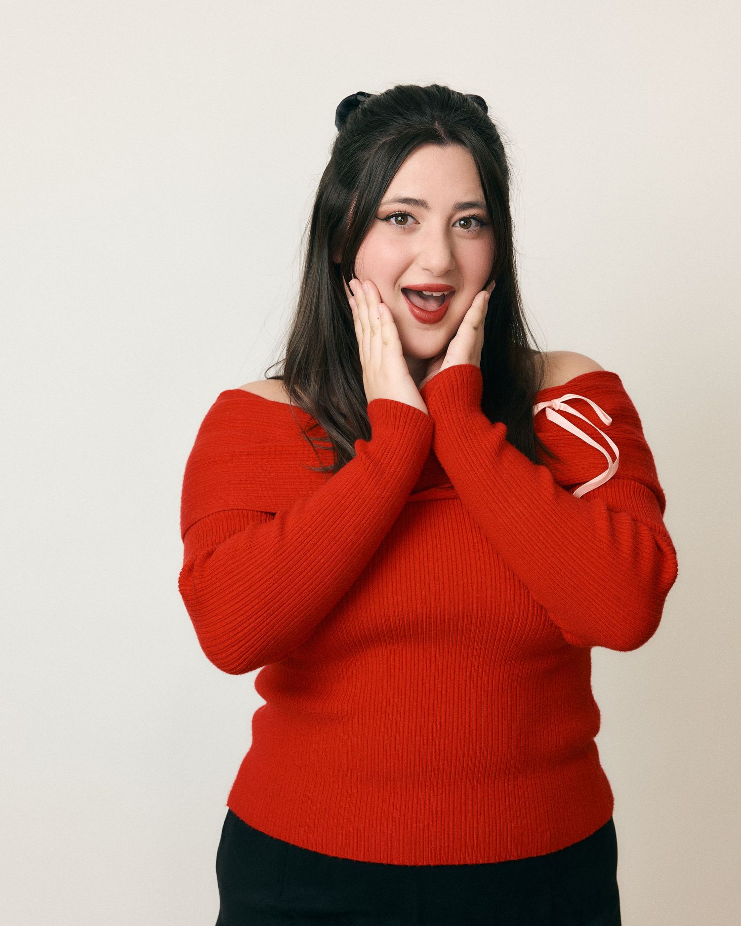 Person in red sweater making playful expressions against white background.