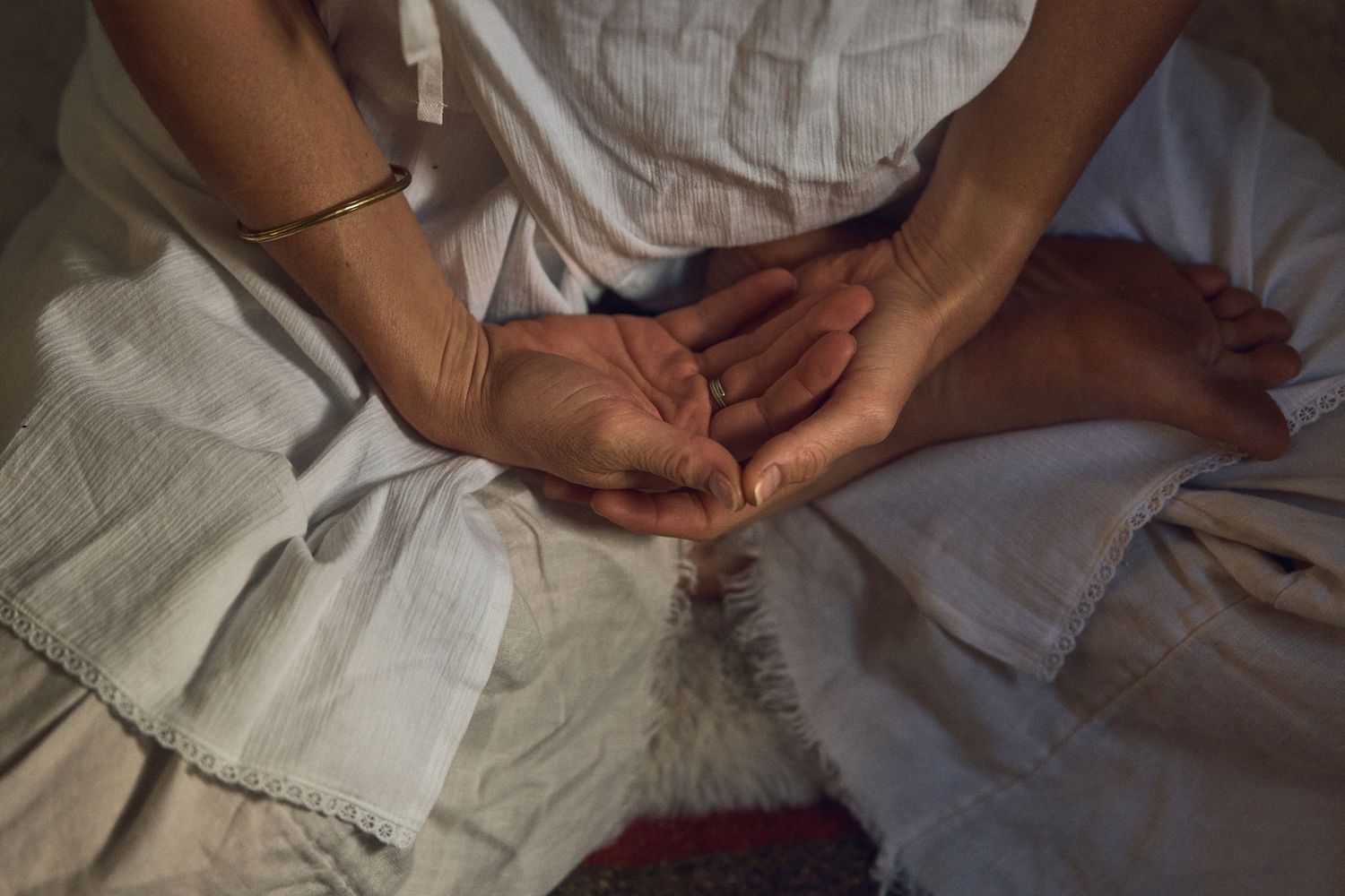 Hands resting on white fabric in soft, natural light.