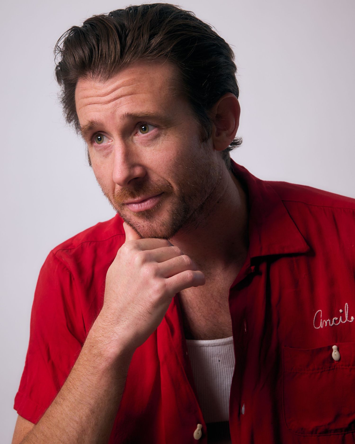 Series of expressive portraits in red polo shirt showing contemplative poses.