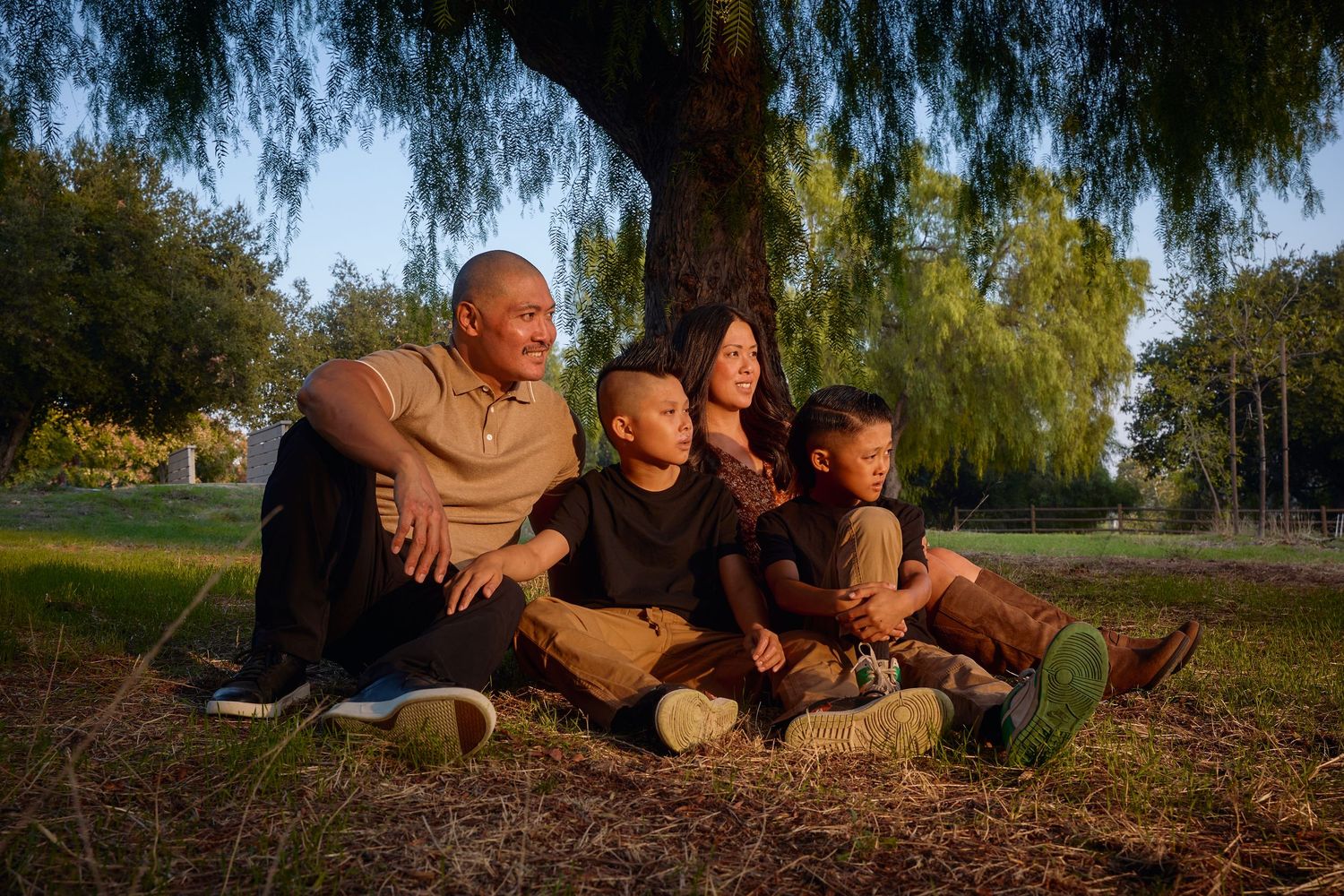 Family outdoor photo session at sunset under willow trees.