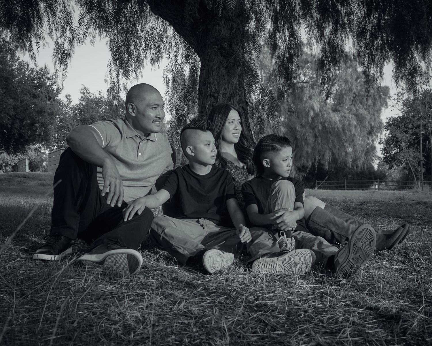 Black and white family portrait series showing intimate moments under willow tree.