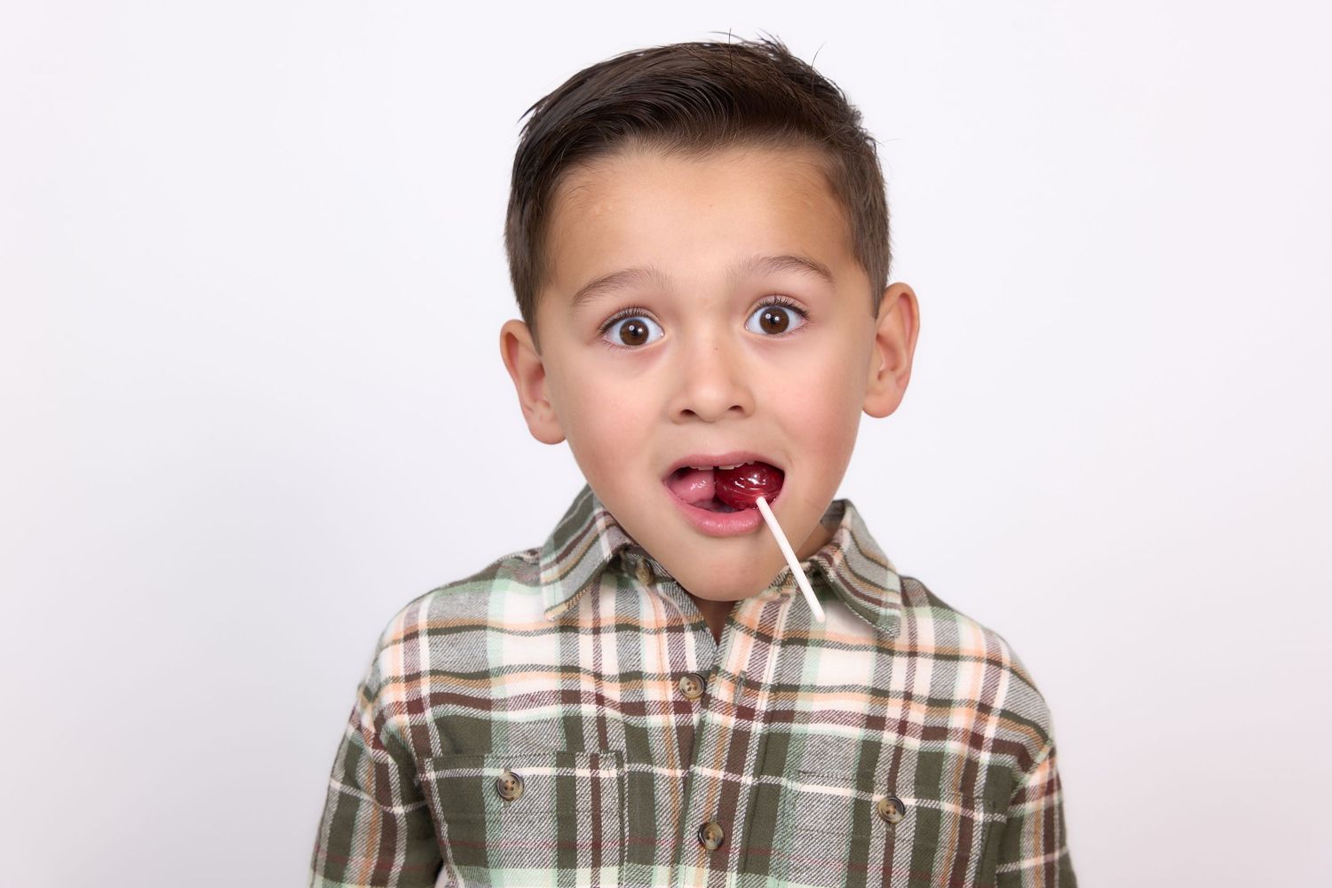 Young boy in plaid shirt making playful expressions in studio portraits against white background.