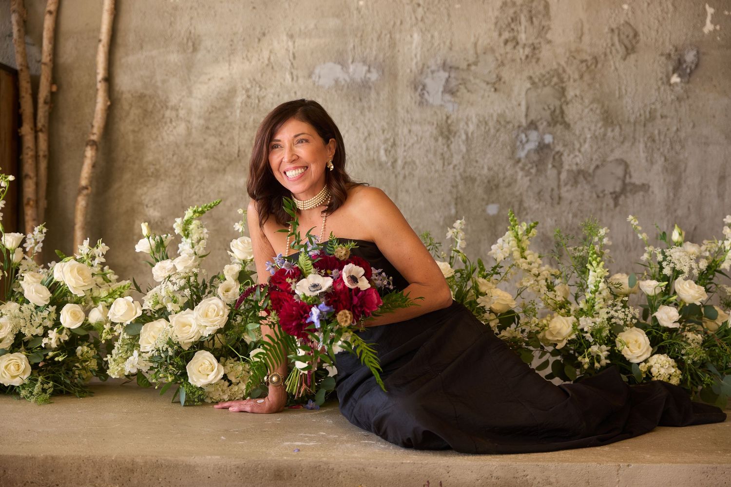 A wedding photo collage showing floral arrangements with white and burgundy flowers against a textured wall backdrop.