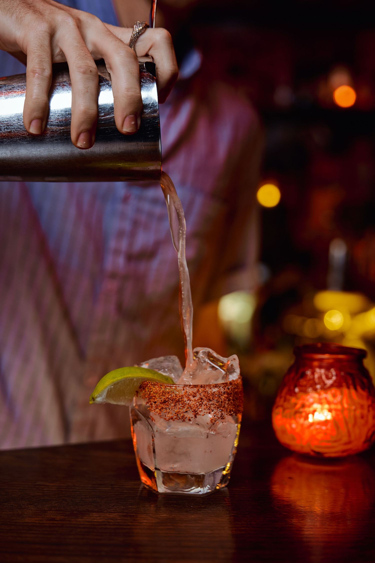 Bartender scooping chocolate ice cream into dessert glasses in a dimly lit bar setting.