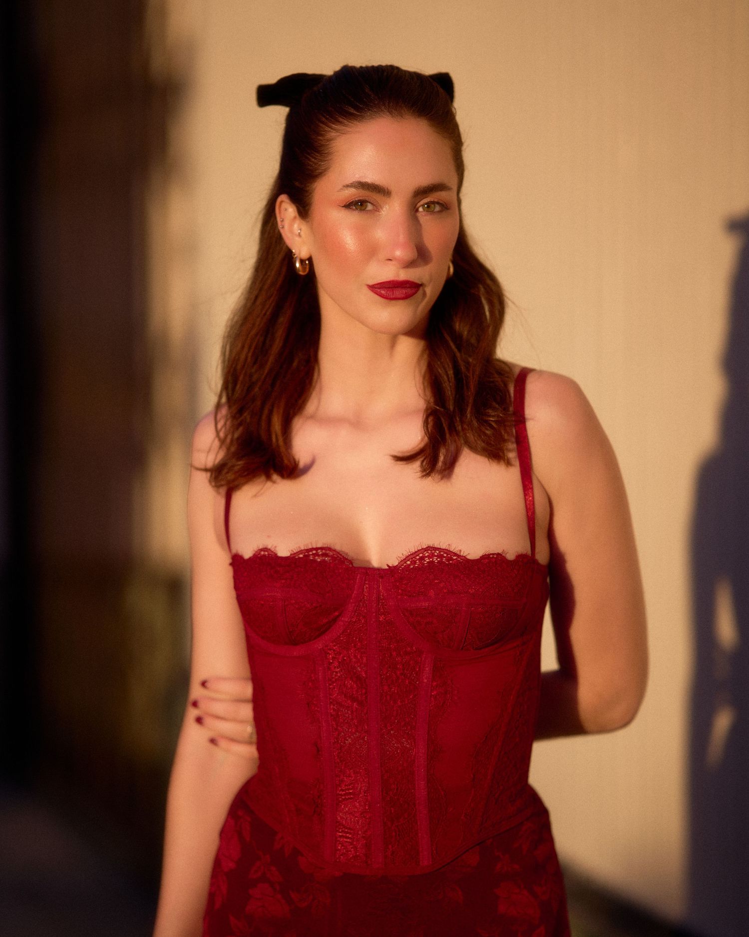 Fashion portrait in red corset dress with warm sunset lighting.