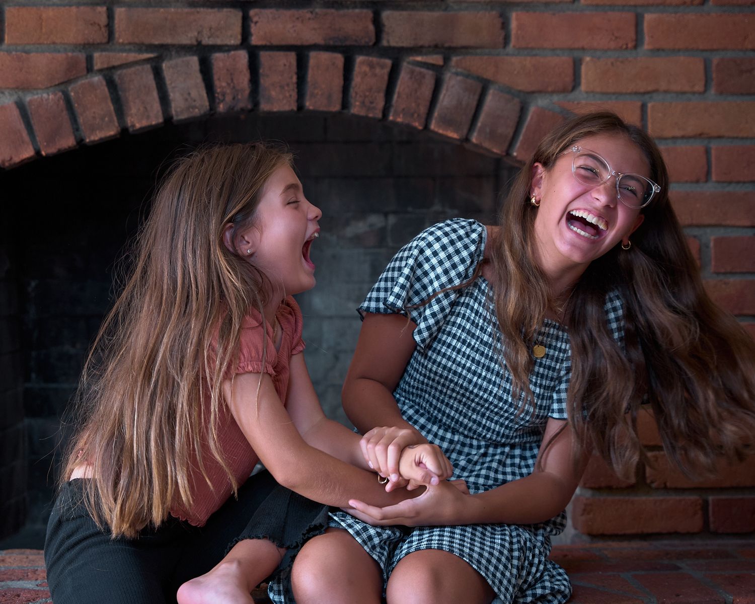 Friends having an animated conversation while relaxing against a brick wall background.