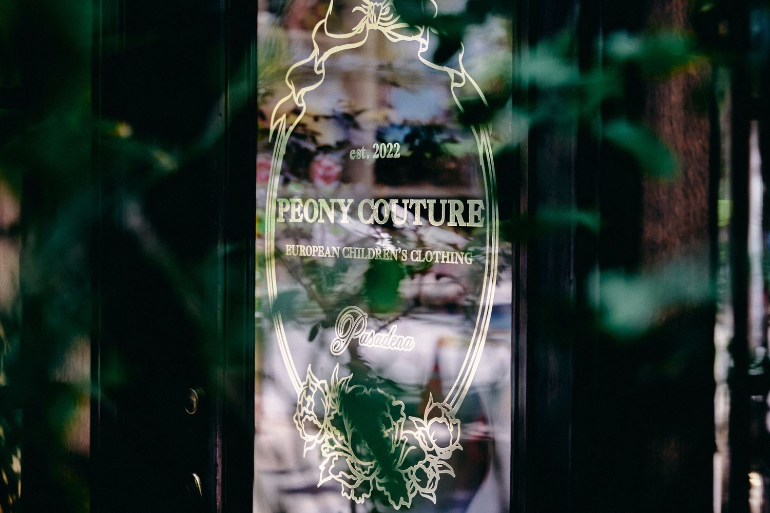 Blurred storefront window with elegant white lettering and decorative floral designs.